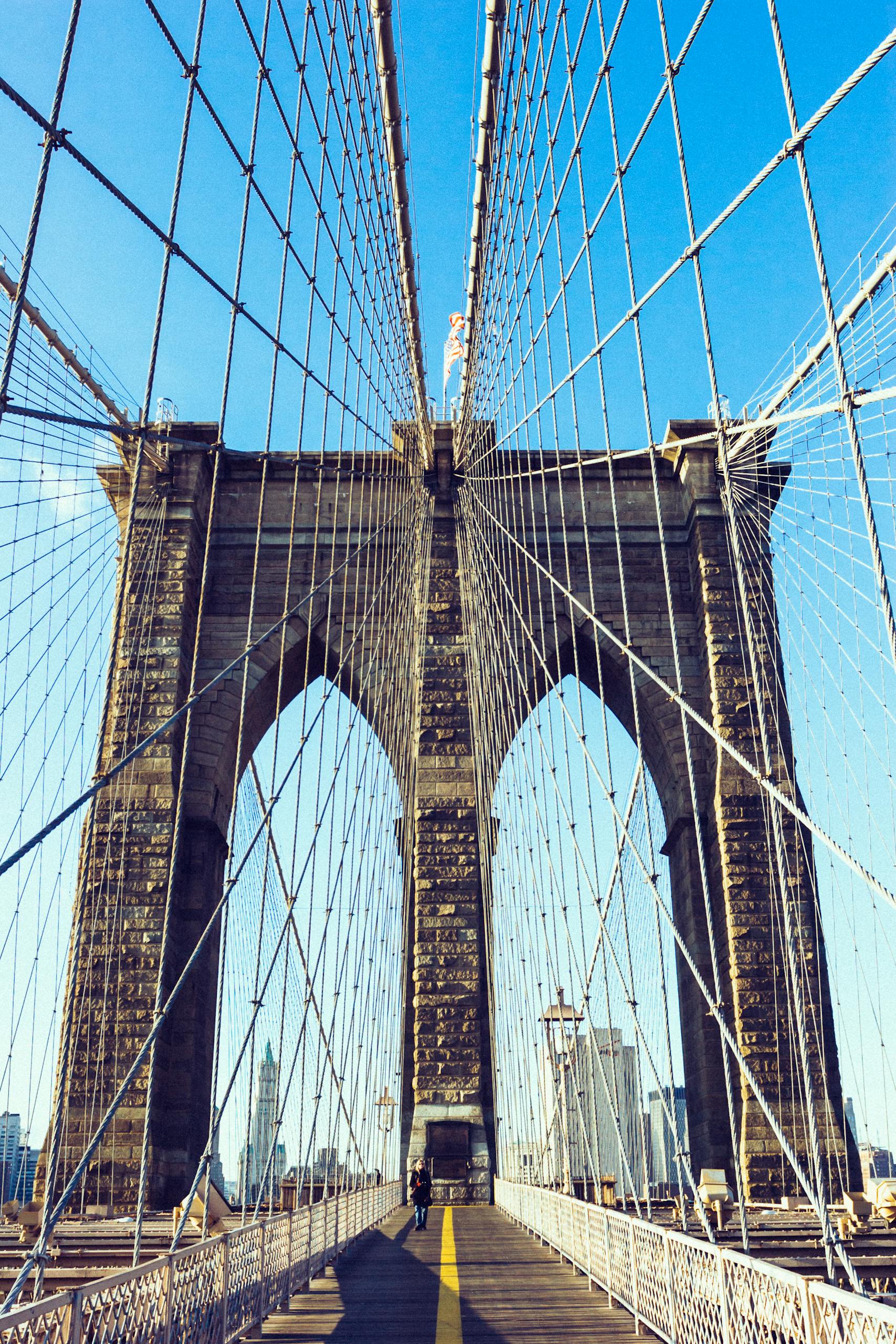View of the iconic Brooklyn Bridge showcasing its architecture under a clear blue sky in New York City.